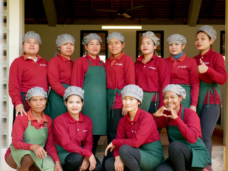 Women working at Senteurs d'Angkor Workshop, engaged in various tasks such as crafting candles, processing coffee beans, and peeling banana stems for weaving.